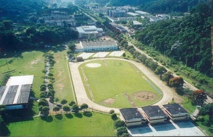 Vista aérea do complexo esportivo da Universidade Federal de Viçosa: pista de atletismo e campo de futebol cercados por mata.